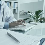 Hands of female doctor typing on keyboard